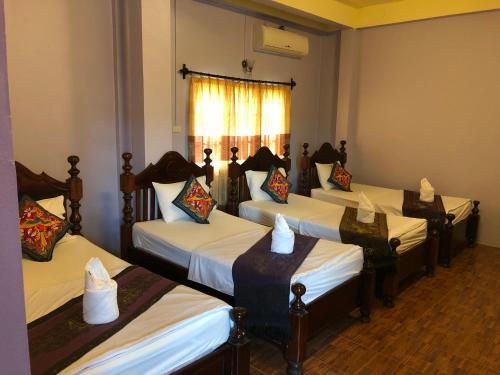 eine Gruppe von 4 Betten in einem Zimmer in der Unterkunft Soutjai Guesthouse & Restaurant in Vang Vieng
