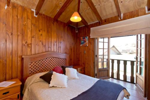 1 dormitorio con paredes de madera y 1 cama con almohadas en Cabañas Orion, en Concón