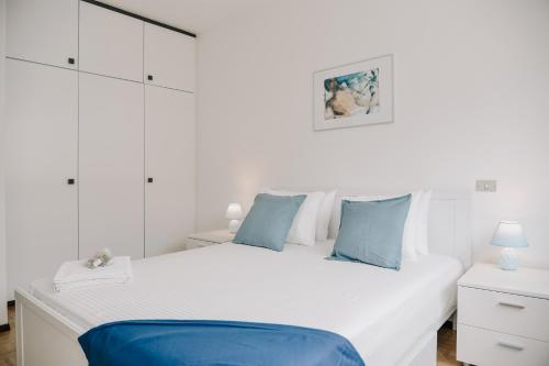 1 dormitorio con 1 cama blanca grande con almohadas azules en Lugano Central Suite Apartment Ciseri en Lugano