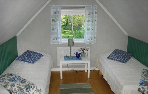 two beds in a room with a table and a window at 2 Bedroom Gorgeous Home In Bodafors in Bodafors