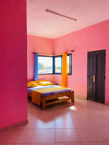 a pink room with a bed and a window at LE JAVA in Antsakomboena
