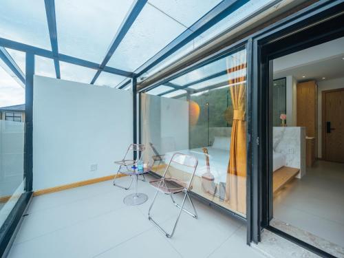 a glass house with two chairs and a table at Moganshan Pinhouwu Hotel in Deqing