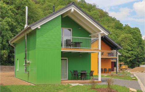 a green tiny house with a balcony and tables at Ferienhausdorf Thale in Thale