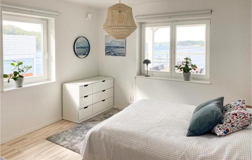 a white bedroom with a bed and two windows at Amazing Apartment In Svanesund With Kitchen in Svanesund