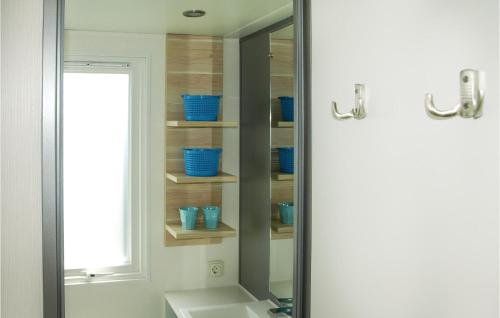 een spiegel in een badkamer met blauwe kommen op planken bij Huisje Blauwe Hoek in Westerland