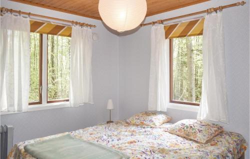ein Schlafzimmer mit einem Bett und zwei Fenstern in der Unterkunft Amazing Home In Asarum With Kitchen in Ljungsjömåla