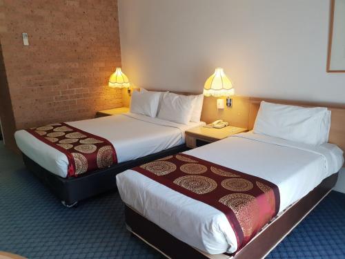 a hotel room with two beds and two lamps at John Hunter Motel Muswellbrook in Muswellbrook