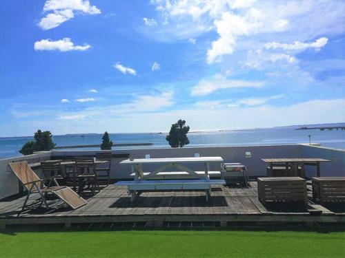 a picnic table and chairs on a deck overlooking the water at 美ら海水族館車で5分/BBQ可能/夕日の見える屋上テラス/4BR一戸建/駐車場3台/最大18名宿泊 in Urasaki