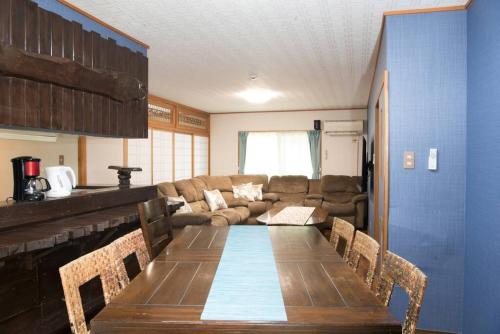 a living room with a table and a couch at 美ら海水族館車で5分/BBQ可能/夕日の見える屋上テラス/4BR一戸建/駐車場3台/最大18名宿泊 in Urasaki