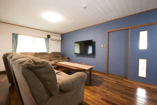 a living room with a couch and a table at 美ら海水族館車で5分/BBQ可能/夕日の見える屋上テラス/4BR一戸建/駐車場3台/最大18名宿泊 in Urasaki
