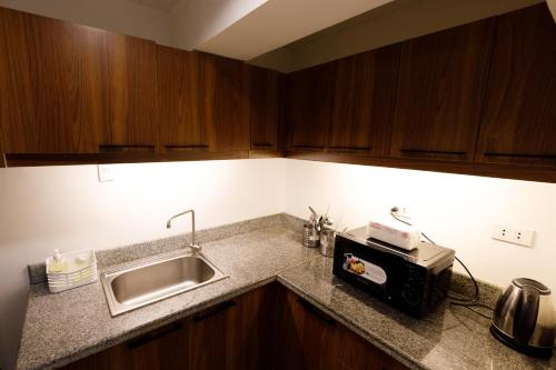 a kitchen counter with a sink and a microwave at 5880 Enriquez Residences in Manila