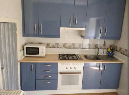 a small kitchen with blue cabinets and a microwave at La Casita de Martina in Sotillo de la Adrada
