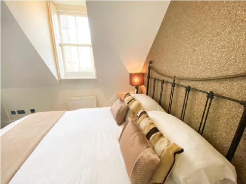 Un dormitorio con una cama con sábanas blancas y una ventana. en Quayside Quarters, en Poole