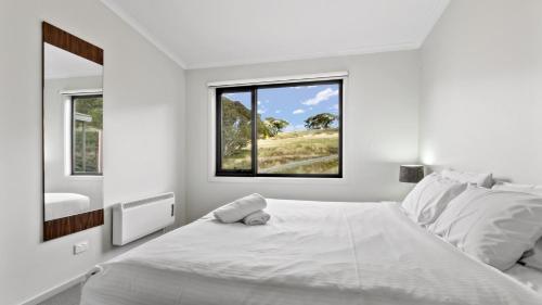 um quarto branco com uma cama grande e uma janela em Higgi Drive 4 em Mount Hotham