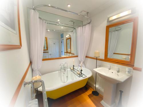 Un baño con bañera, lavabo y espejo. en Quayside Quarters, en Poole