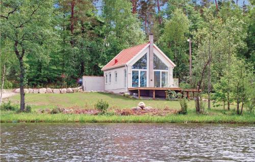 a small house with a red roof next to a body of water at Cozy Home In Åsljunga With Kitchen in Åsljunga