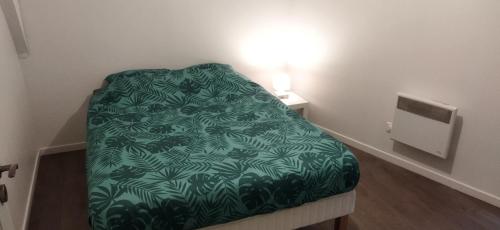 ein kleines Zimmer mit einem Bett mit einer grünen Decke in der Unterkunft Appartement en duplex à Hébuterne, avec lave linge in Hébuterne