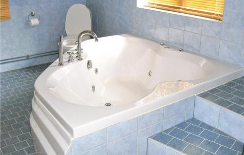 een wit bad in een blauwe betegelde badkamer bij Stunning Home In Stde With Kitchen in Stor-Hullsjön