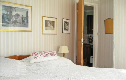 ein Schlafzimmer mit einem weißen Bett und Bildern an der Wand in der Unterkunft Lovely Apartment In Ljugarn With Kitchenette in Lau