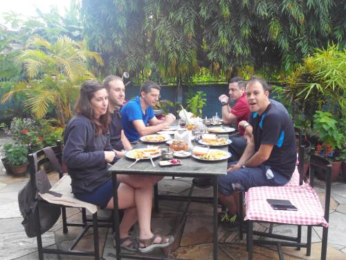 een groep mensen die aan een tafel zitten en eten bij Hotel Fishtail Villa in Pokhara