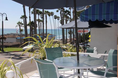 a table and chairs with an umbrella and the ocean at Sea Horse Resort in San Clemente