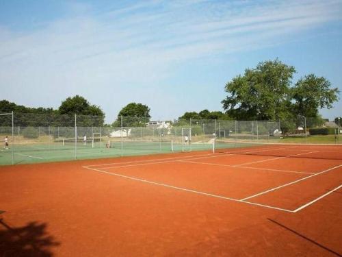 a tennis court with people playing on it at Résidence l’Esprit de la mer in Combrit