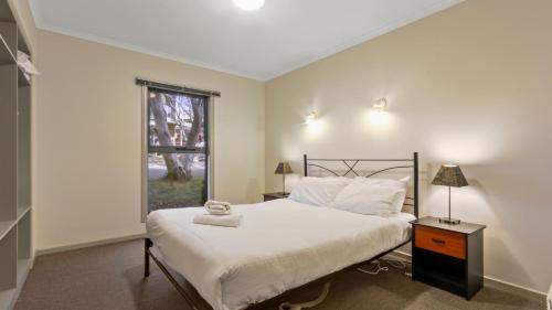 ein Schlafzimmer mit einem großen Bett und einem Fenster in der Unterkunft Karoondah 10 in Mount Hotham