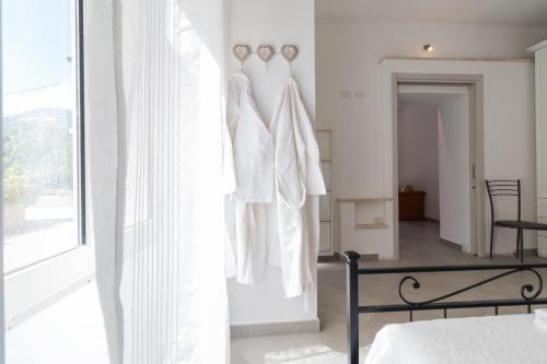 a bedroom with two white dresses hanging on a wall at Gurosai in Dorgali