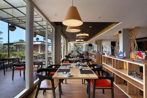 a restaurant with wooden tables and chairs and windows at Azana Boutique Hotel Denpasar in Denpasar