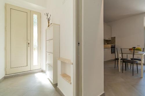 a kitchen and dining room with white walls and a door at Gurosai in Dorgali