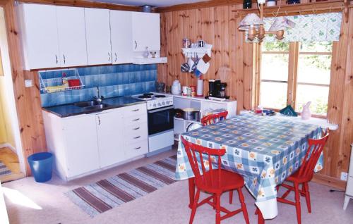 une cuisine avec une table avec des chaises rouges et une cuisinière dans l'établissement Holiday Home Rådetorps Gård Storfors, à Rådetorp