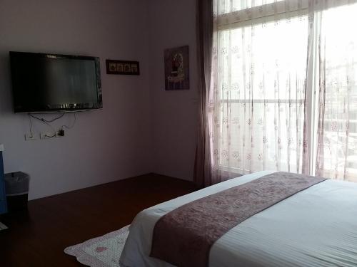 a bedroom with a bed and a flat screen tv at Jing Xiang Hua Nong B&B in Dongshan