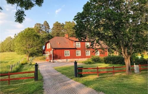 a red house with a fence in front of it at Cozy Home In Mantorp With Wifi in Mantorp