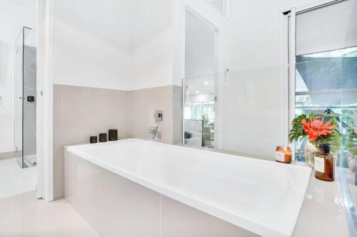 a white bathroom with a large window and a white sink at Villa Vihara Rainforest Penthouse in Innisfail