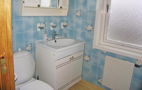 a blue tiled bathroom with a toilet and a sink at Stunning Home In Kalv With Kitchen in Kalv