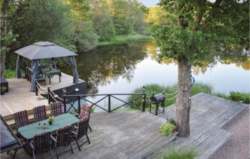 a wooden deck with a table and chairs next to a lake at Lovely Home In Klippan With Sauna in Klippan