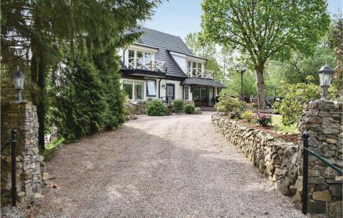 a house with a stone fence and a driveway at Lovely Home In Klippan With Sauna in Klippan