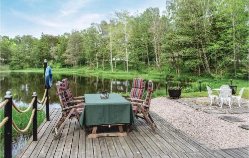 a table and chairs on a wooden deck next to a lake at Lovely Home In Klippan With Sauna in Klippan