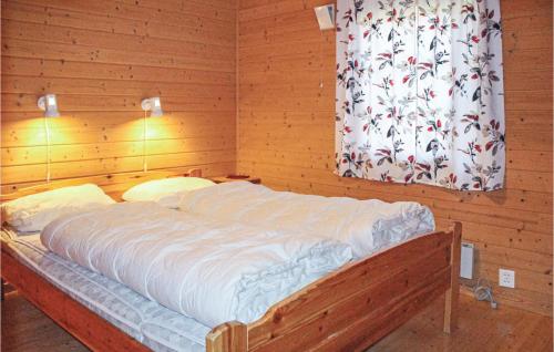 a large bed in a wooden room with a window at Nice Home In Lavik With 3 Bedrooms And Wifi in Lavik