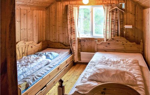 two beds in a wooden room with a window at 6 Bedroom Amazing Home In Hydalsmo in Ofte