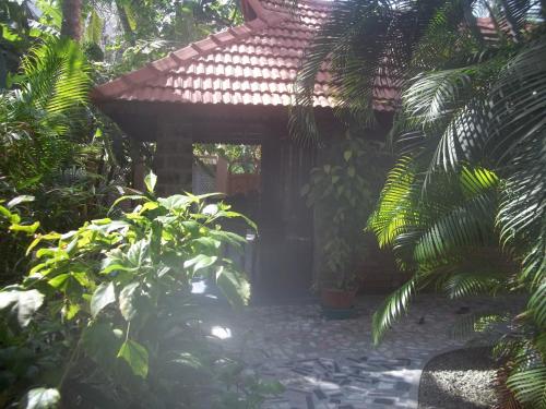 a small house in a garden with plants at Maharaju Palace in Kovalam