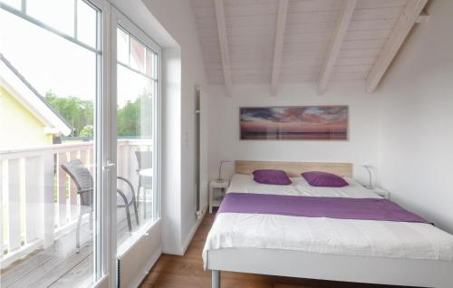 Schlafzimmer mit einem Bett mit lila Kissen auf dem Balkon in der Unterkunft Seehund 5 in Süssau