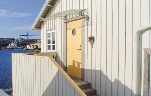 a building with a yellow door and stairs next to the water at Beautiful Apartment In Skärhamn in Skärhamn