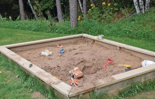 a sandbox filled with sand and toys in a yard at Cozy Home In Jönköping With Wifi in Norrahammar