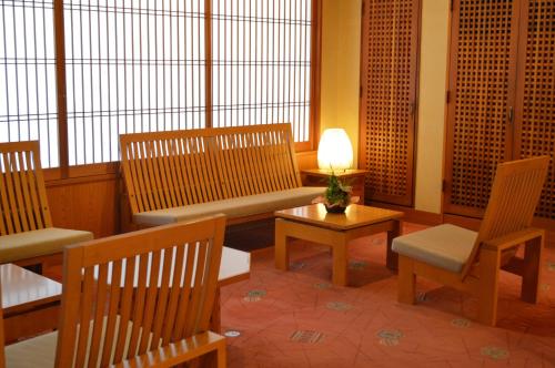 a room with wooden chairs and a bench and a table at Yumotoya in Matsumoto