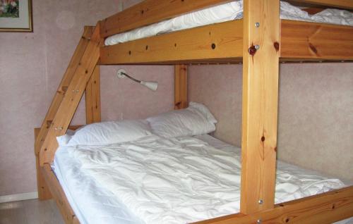 a wooden bunk bed with white sheets and a white bed at Holiday Home Lärbro 46 in Valleviken