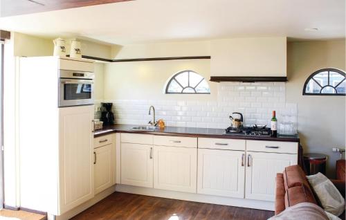 a kitchen with white cabinets and two windows at Hoeve Alegria in Hoogwoud