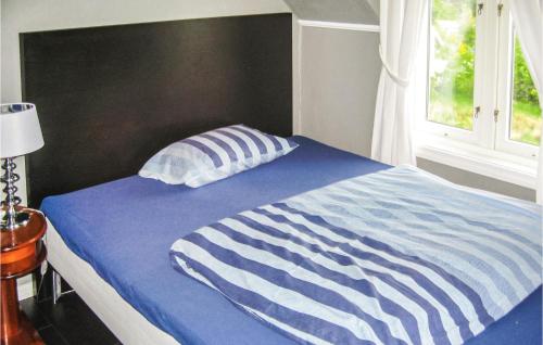 a bed with a blue and white striped comforter and a window at 4 Bedroom Stunning Home In Rong in Rong