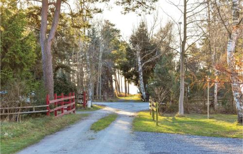 a dirt road through a forest with a red fence at Two-Bedroom Holiday Home In Loderup in Löderup