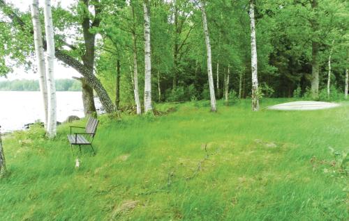 a bench sitting in the grass next to a lake at 1 Bedroom Awesome Home In Lagan in Lagan